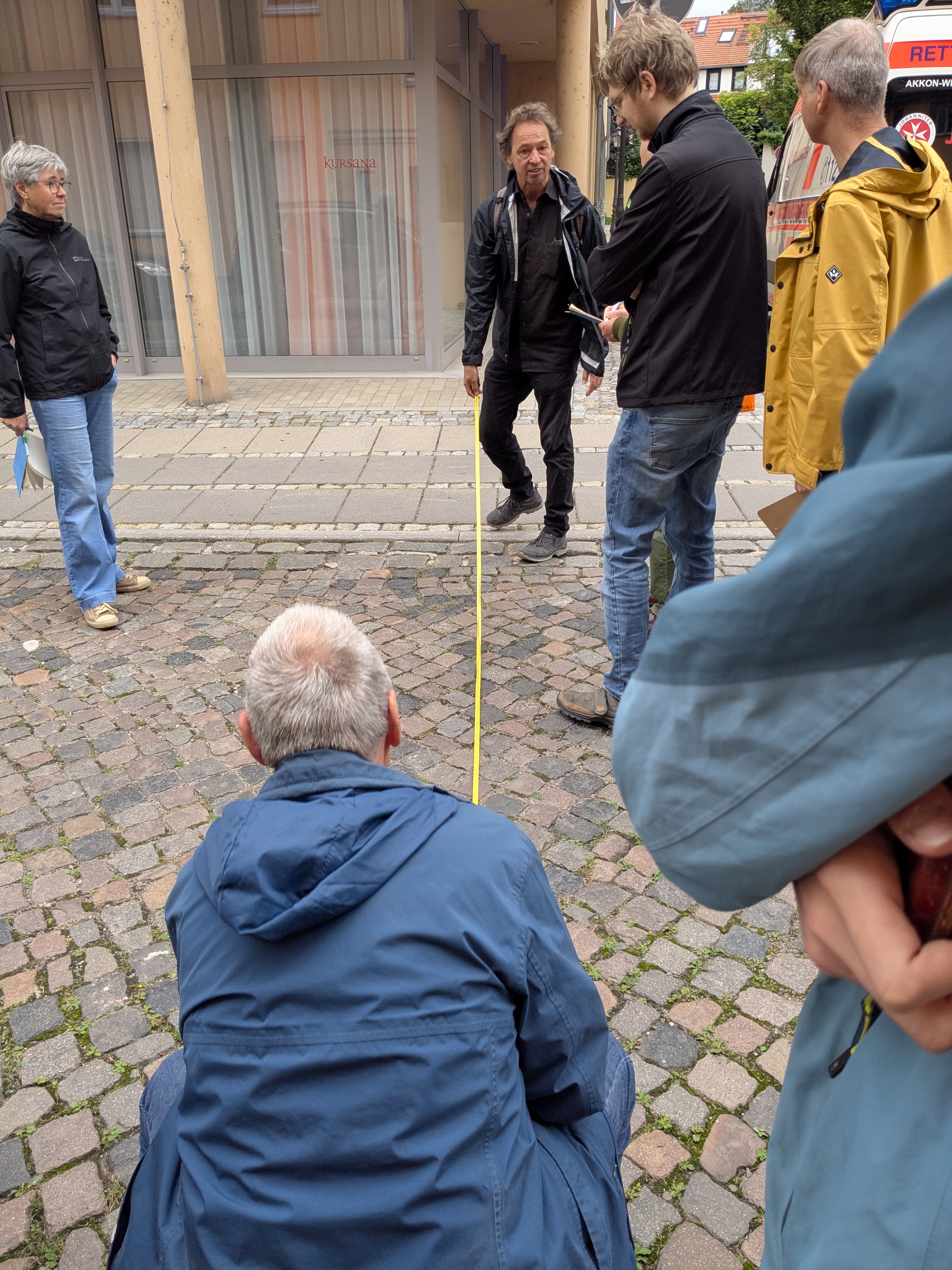 Teilnehmende des VCD-Aktiventags untersuchen bei einem Stadtrundgang eine gepflasterte Fläche und messen Abstände mit einem Maßband.